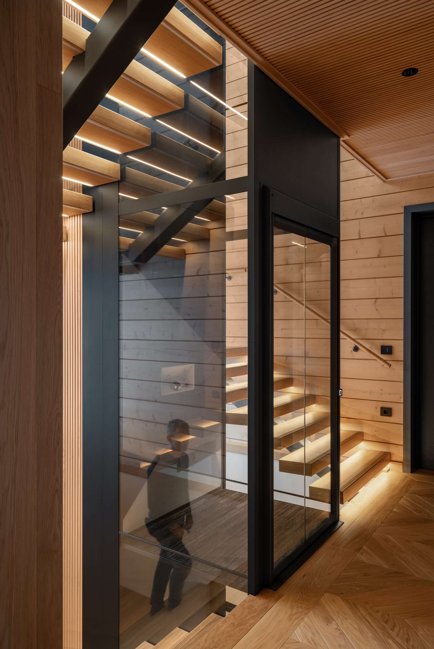 Timber-lined stair hall with a glazed lift