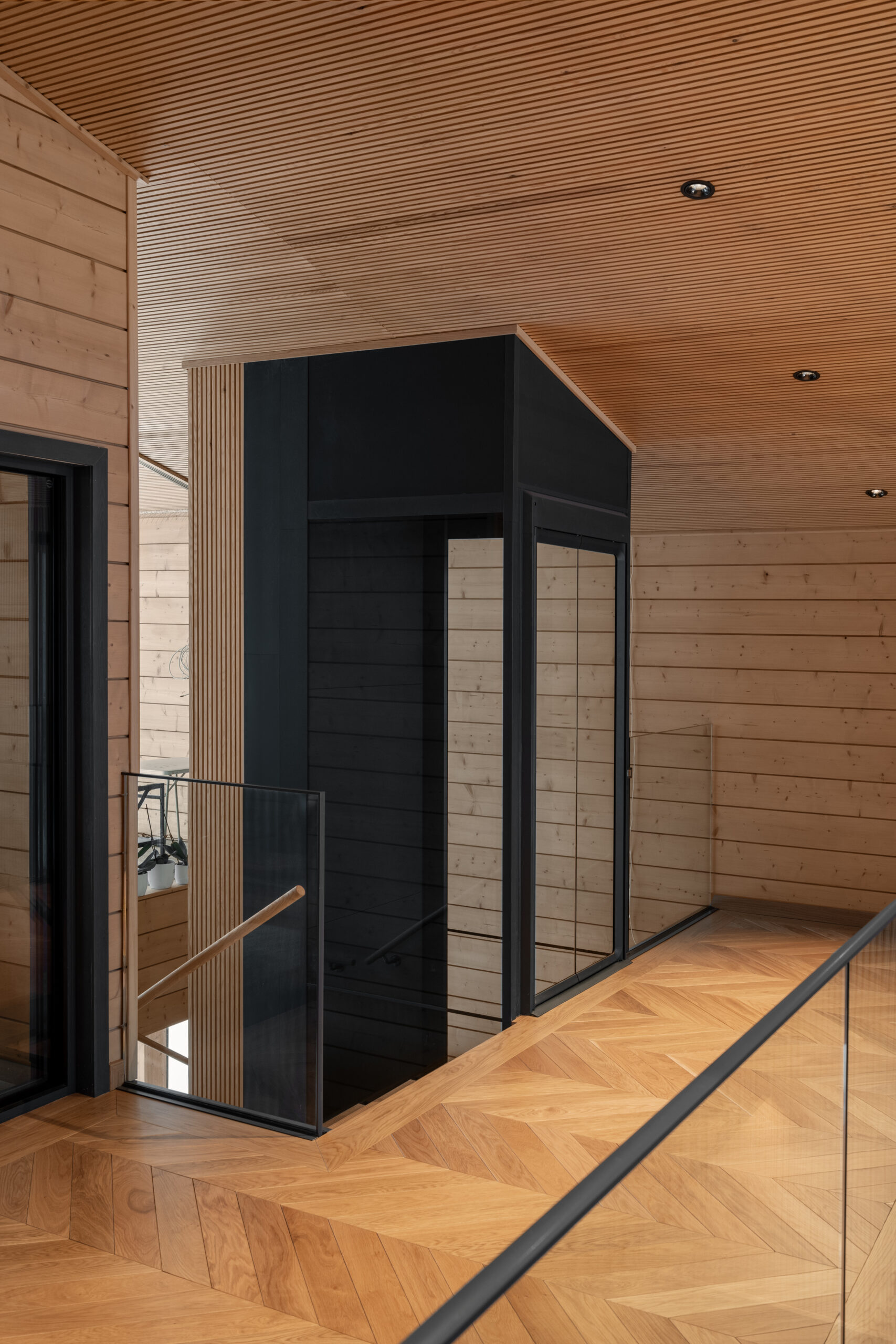 Upper hall with a glazed lift and herringbone timber floor